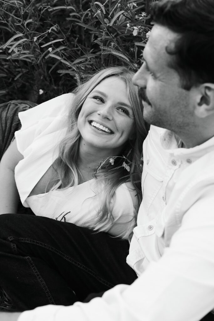 black and white portrait in a field of a newly engaged couple staring lovingly at one another -bisoux de lune meagan reily