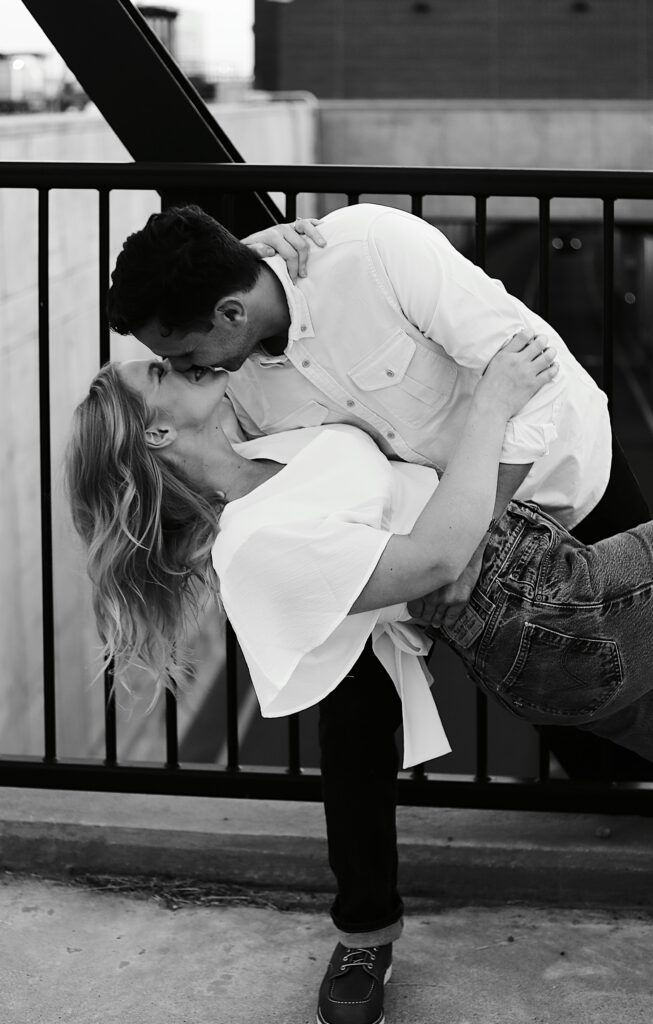 black and white cityscape photograph of a blonde woman being dipped and kissed by a handsome brunette man over the top of a tunnell -bisoux de lune meagan reily