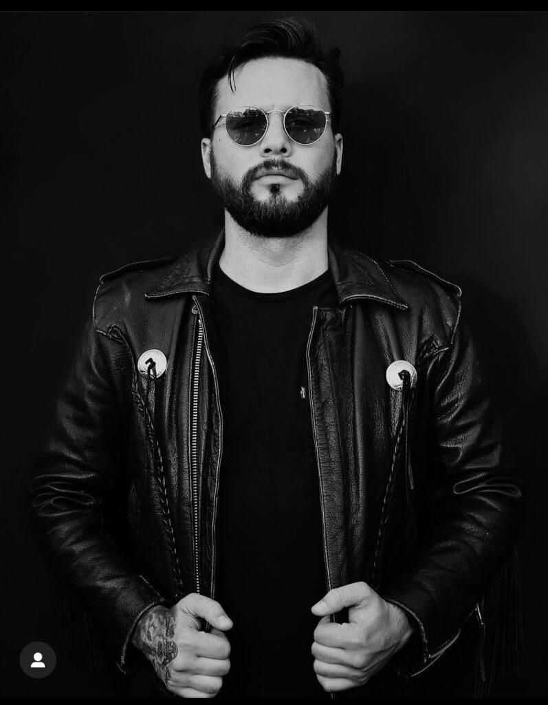 high contrast photo of a musician in sunglasses and a black leather jacket with a very rock and roll edgy country theme and he has a tattooed hand - bisoux de lune meagan reily