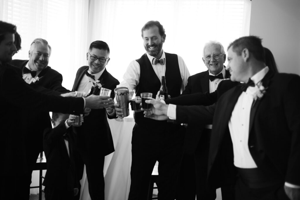 black and white photograph of groom and his groomsmen as they cheers for the day -bisoux de lune meagan reily