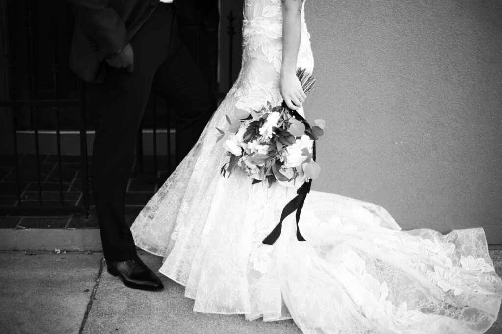 black and white up close photograph of a bride and groom holding flowers up against a wall -bisoux de lune meagan reily